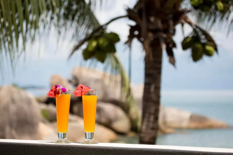 Two fresh juices on a ledge above the rocks and the sea